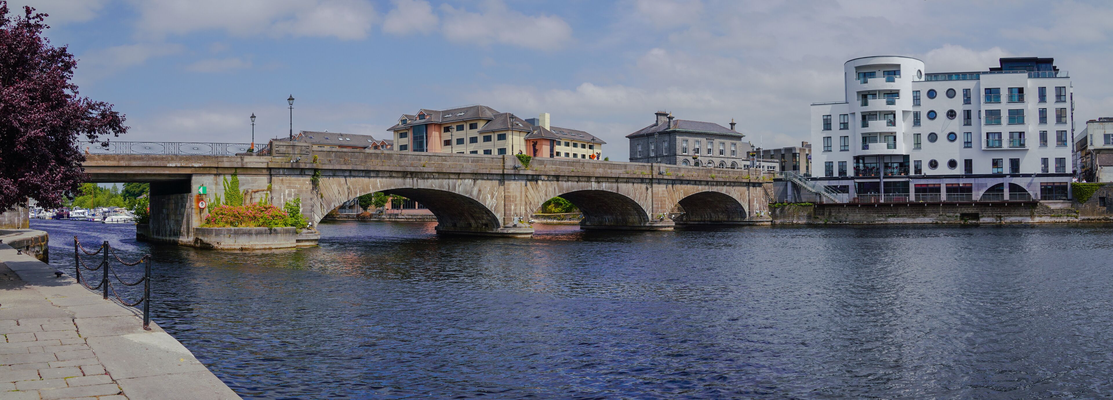 A stone bridge over a river, with buildings on either side.