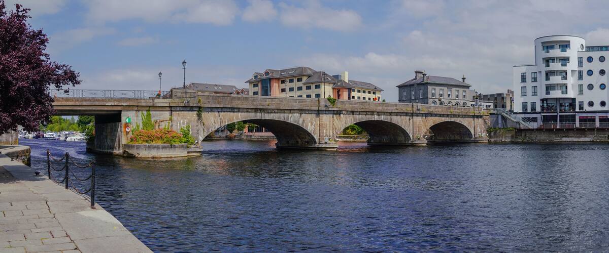 A stone bridge over a river, with buildings on either side.