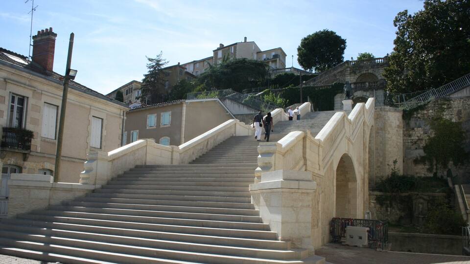 A stone staircase leading up to a building with a wrought iron railing.