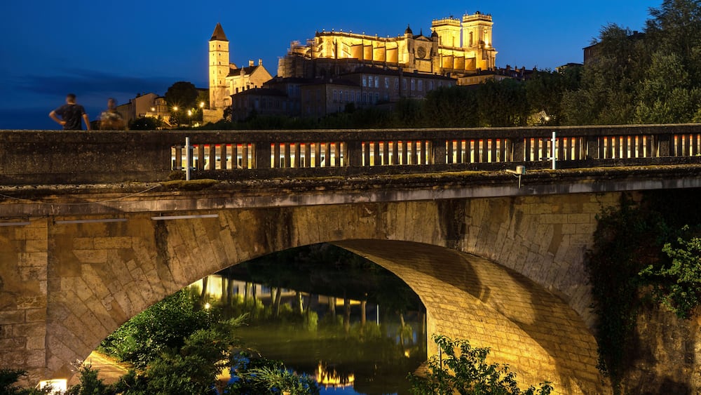 A stone bridge over a river with a castle in the background.