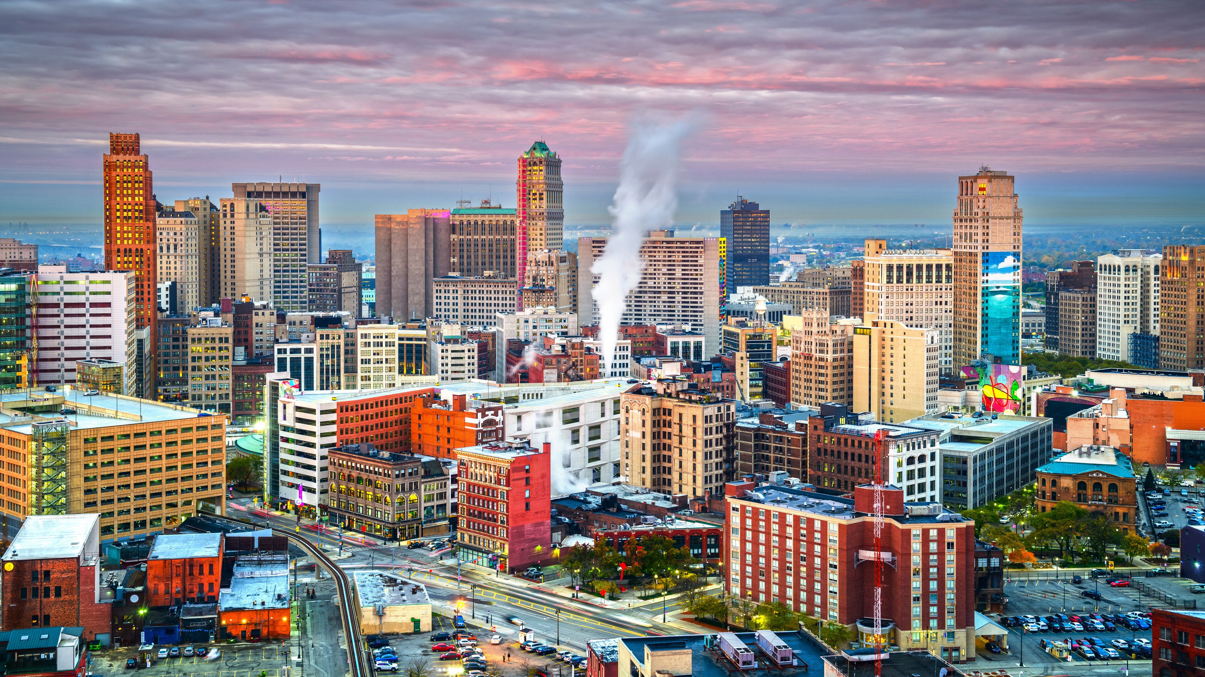 A cityscape with tall buildings, a prominent red building with smoke, and a colorful mural.