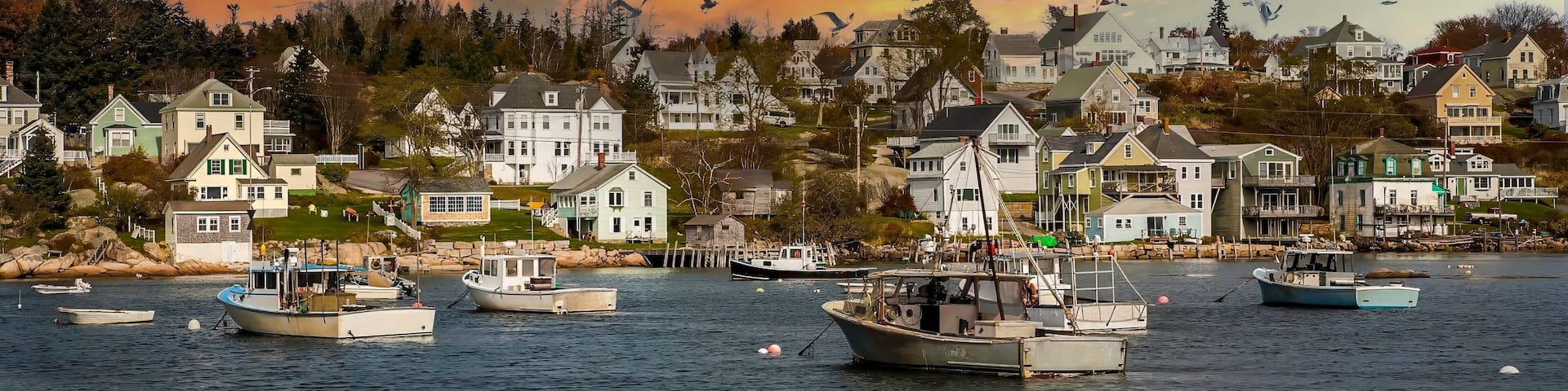Lobster boats anchored in Stonington bay with city in background.