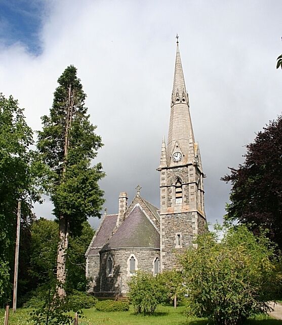 A church with a tall spire and a smaller building with a clock.