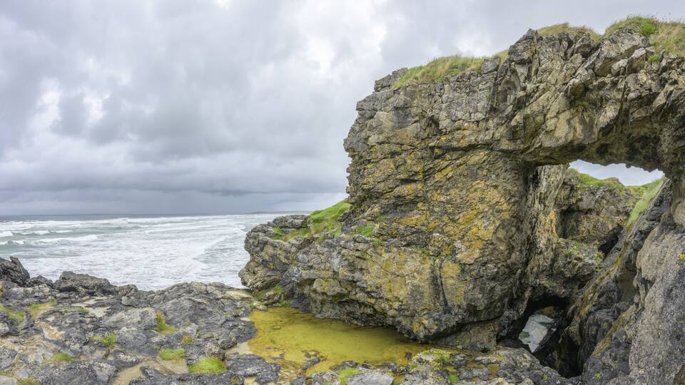 A rocky coastline with a natural arch formation.
