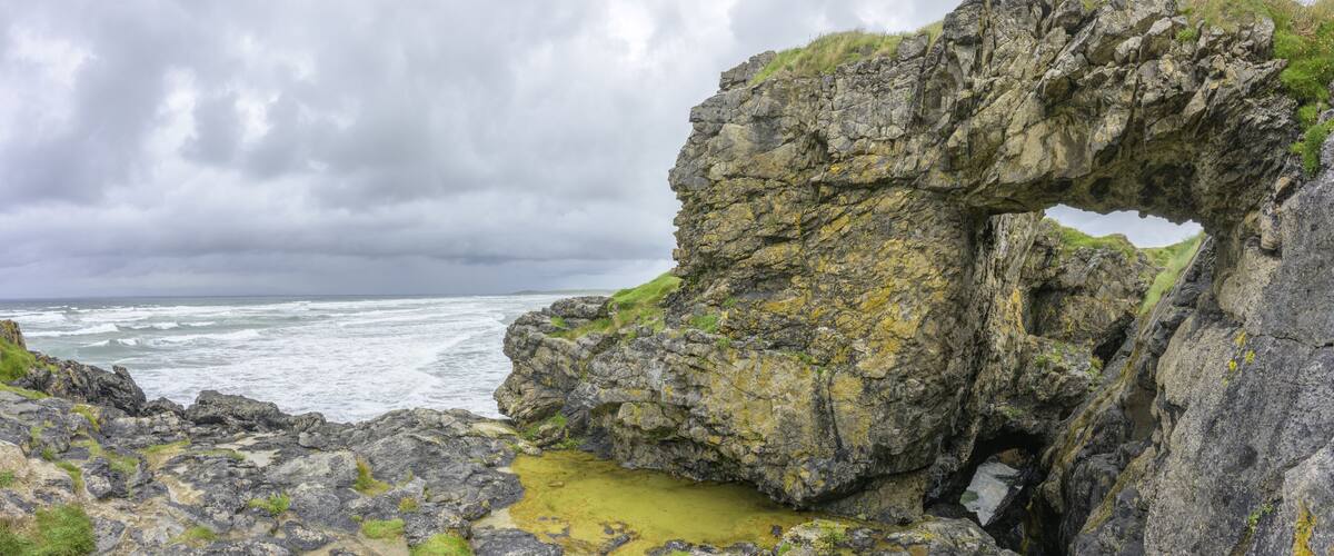 A rocky coastline with a natural arch formation.