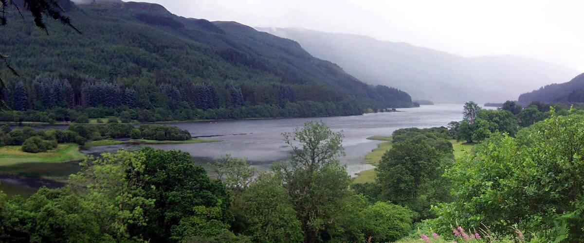 A river winding through a forested valley with hills in the background.