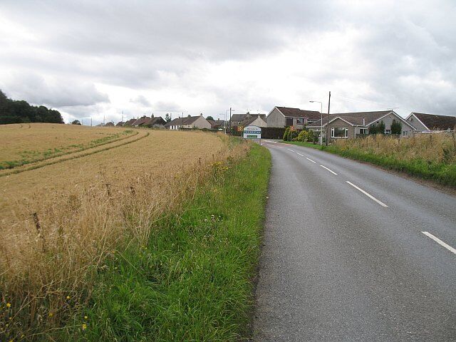 Craigrothie Ceres Road entering Craigrothie. Wheat field on the left.