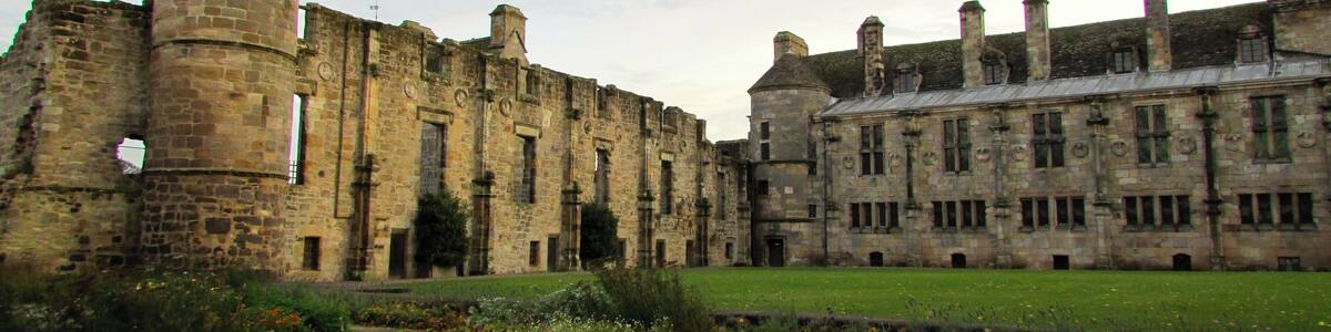 Un bâtiment historique en pierre, doté d’une tour et d’une vaste cour intérieure.