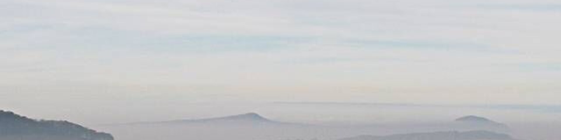 A misty landscape with rolling hills and a grassy foreground.