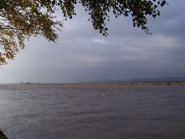 Un río con una orilla lejana y cielo nublado.