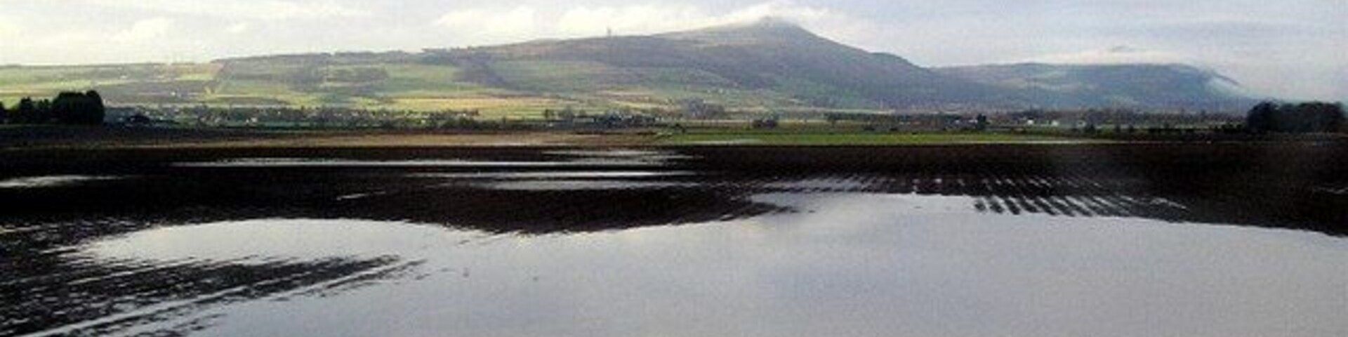 Flooded fields Flooded fields following heavy January rain in the foreground, with the Lomond hills in the background. Taken from the train with the village of Freuchie disappearing to the left.