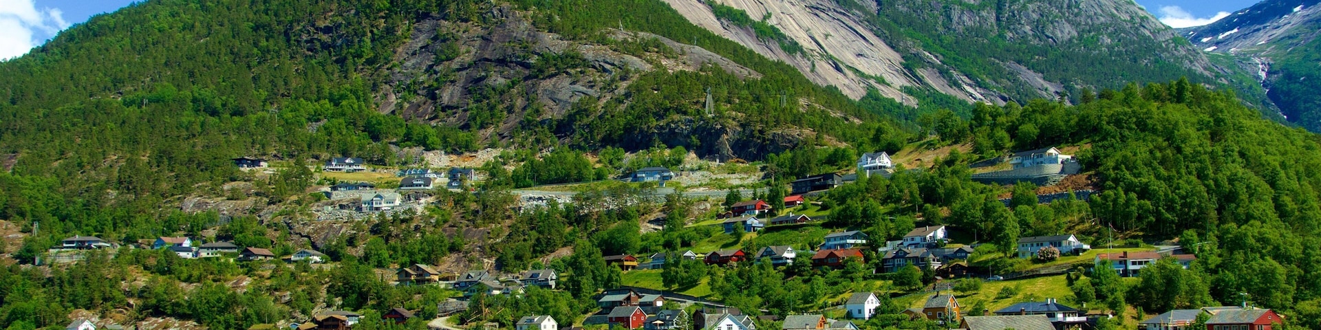 A mountainous landscape with a lake, houses, and a prominent rocky peak.