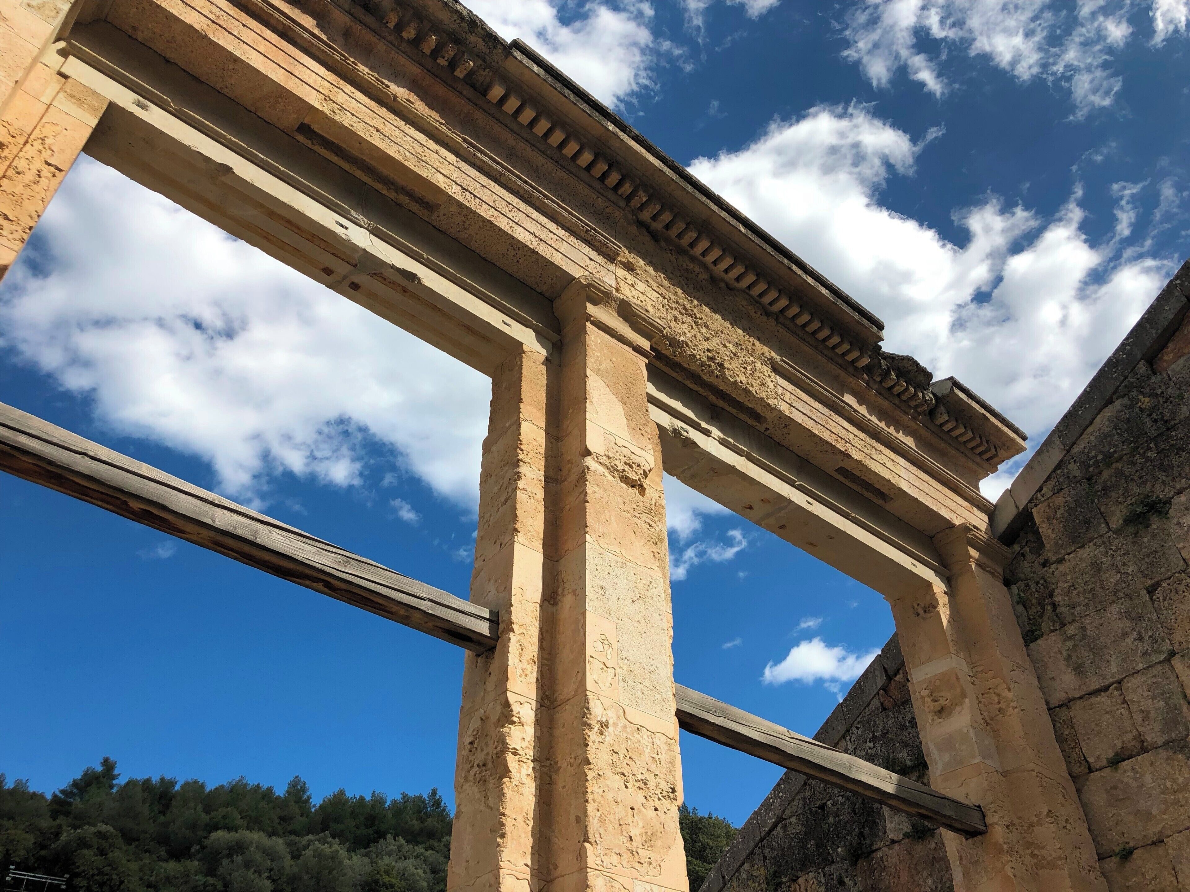 An ancient stone structure with large columns and a clear blue sky.