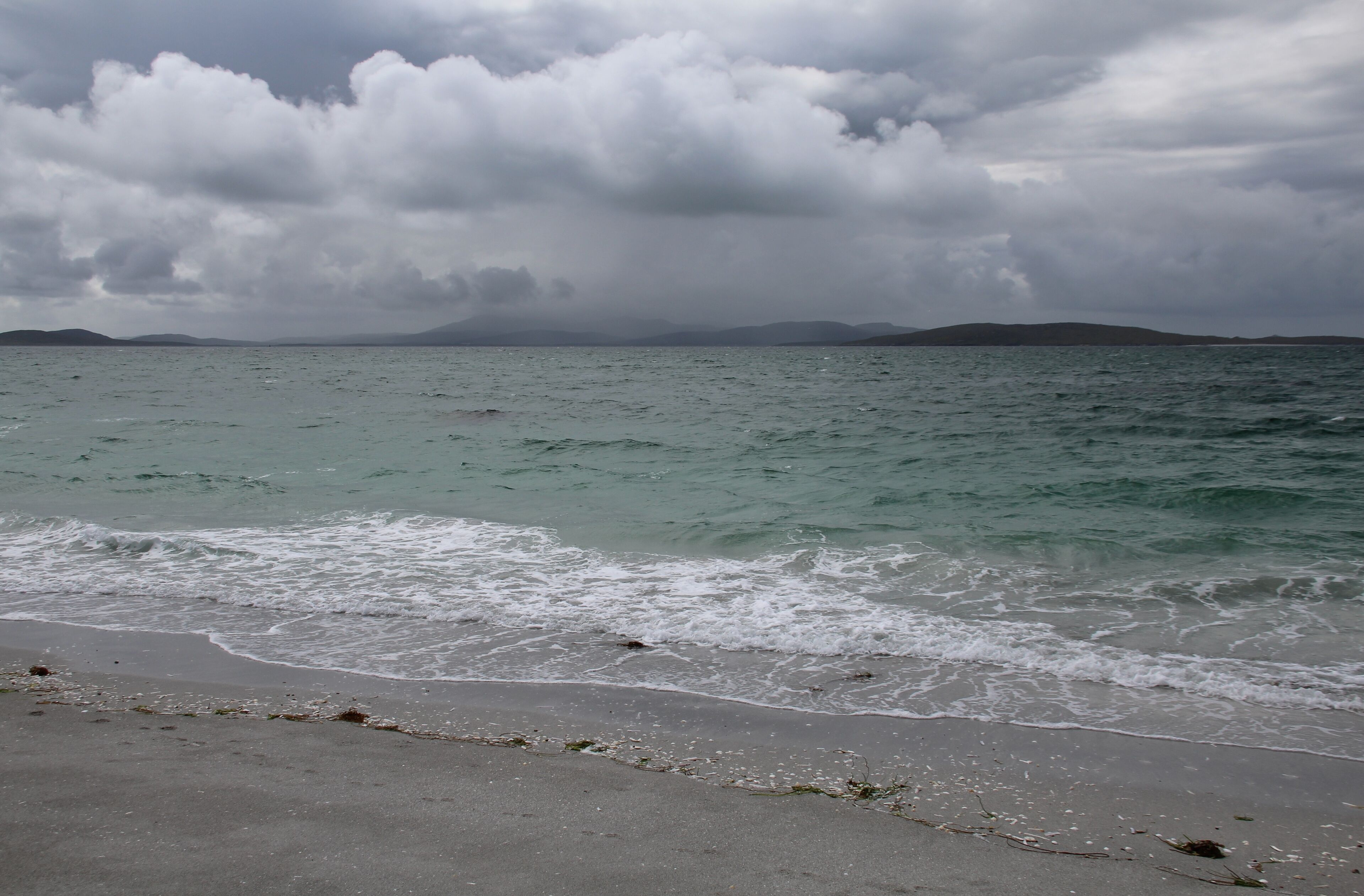 A beach with waves crashing onto the shore under a cloudy sky.