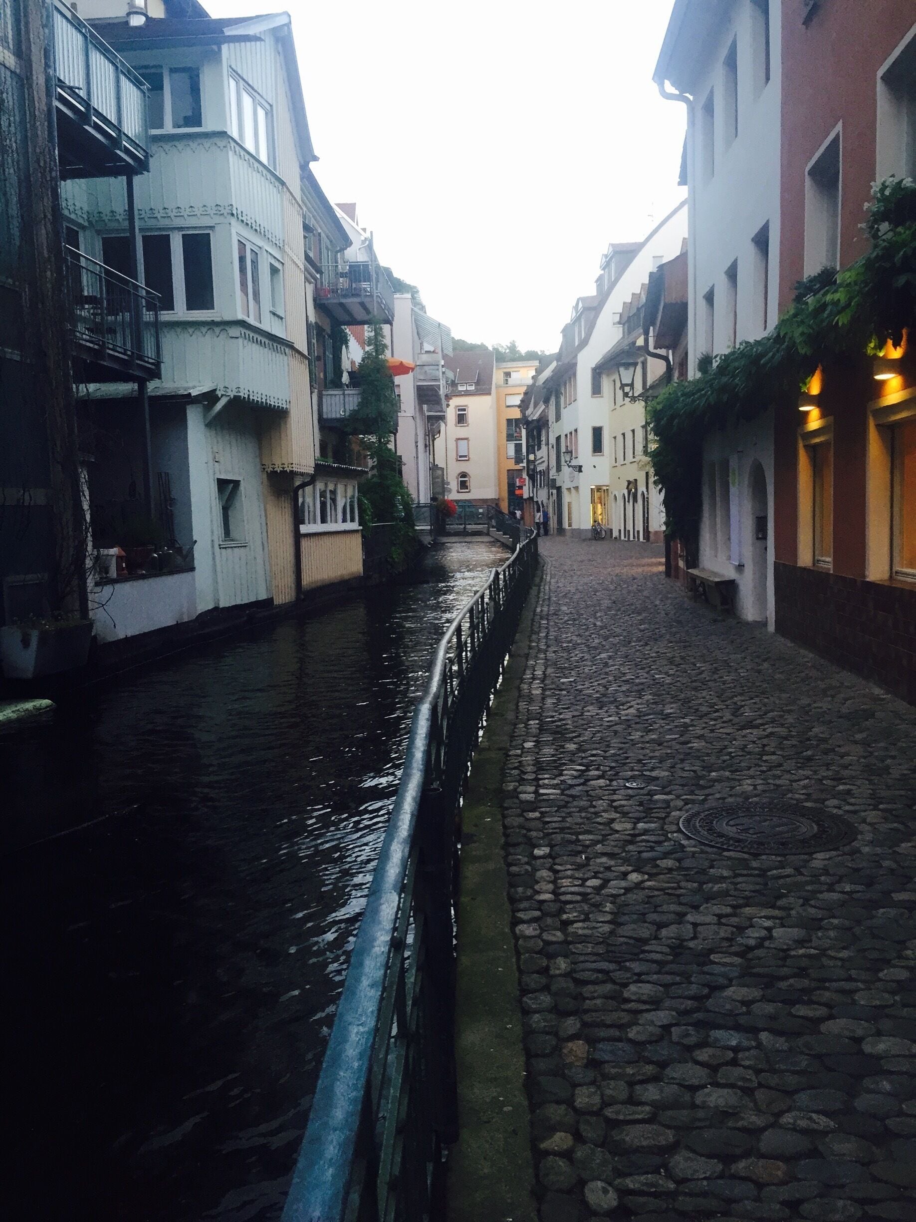 Una estrecha calle adoquinada bordeada por edificios con balcones y un canal.