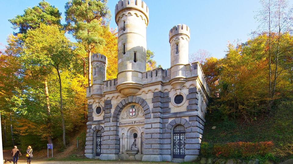 A castle-like structure with two towers, surrounded by autumn-colored trees.