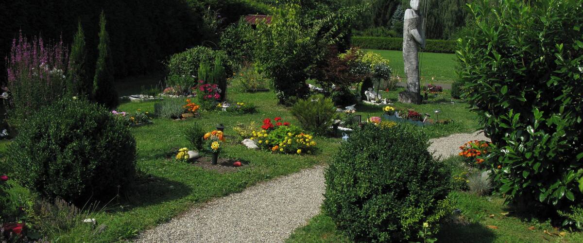 A garden with a gravel path, various flowers, and a statue.