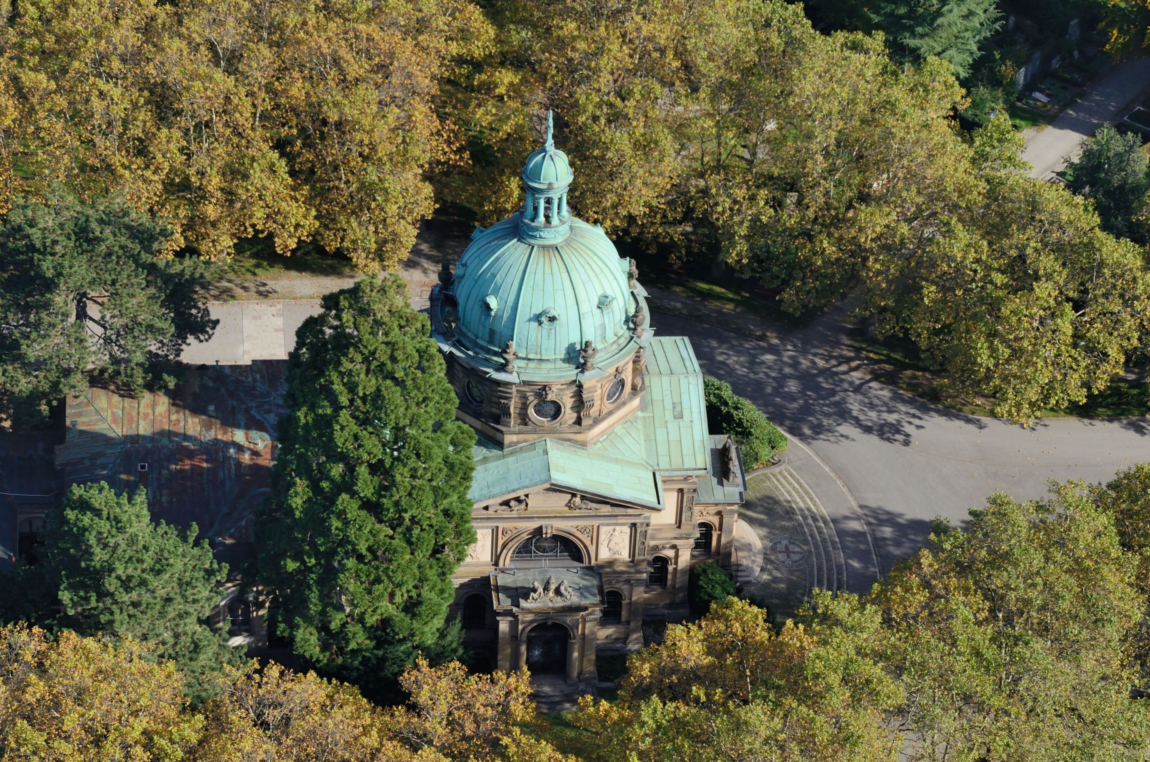 An aerial view of a historic building with a large dome, surrounded by dense trees.