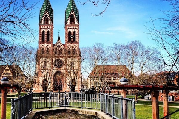 Eine historische Kirche mit zwei grünen Türmen und einem Glockenturm.