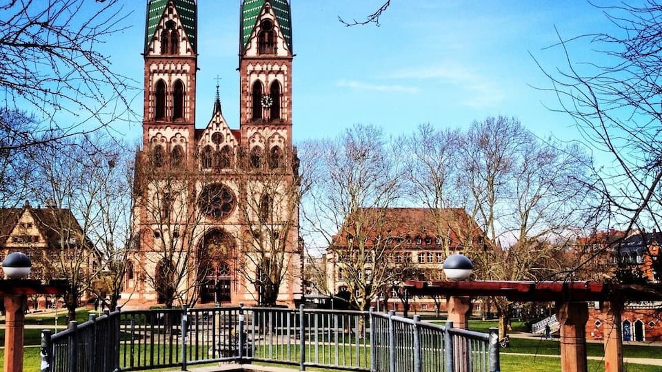 A historic church with two green spires and a clock tower.