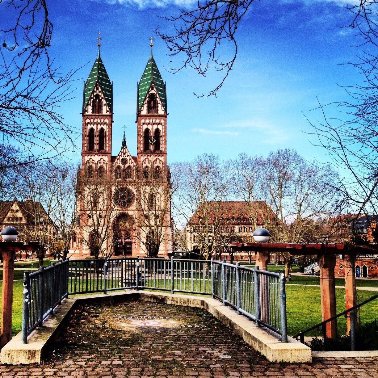 A historic church with two green spires and a clock tower.