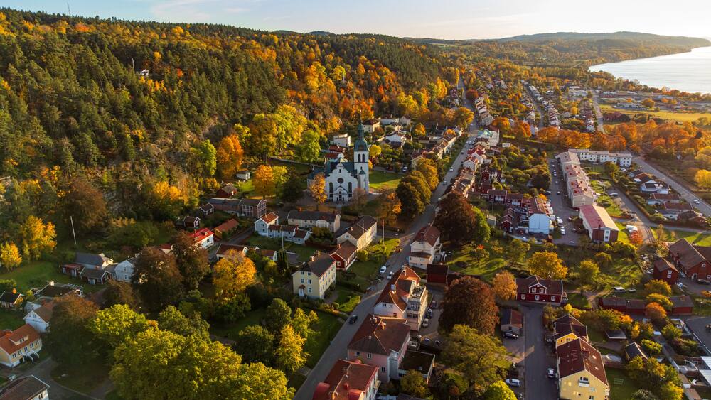 Une ville avec une église, des maisons et une colline boisée.