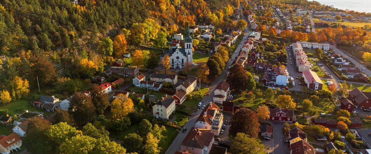 A town with a church, houses, and a forested hillside.
