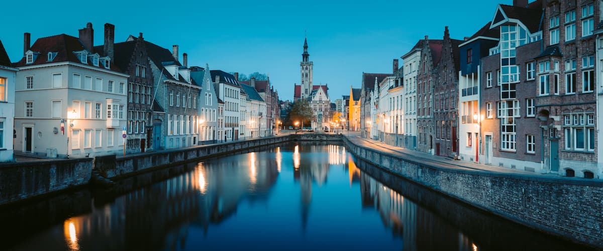 A canal with buildings on either side, a tower in the distance, and a clear sky.