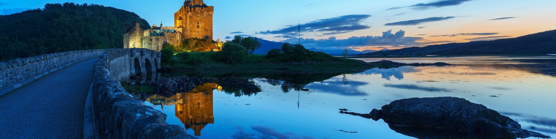 Um castelo à beira de um lago calmo ao entardecer.