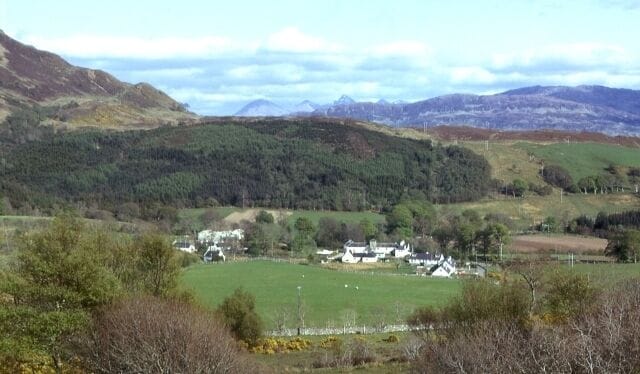 Balmacara Square. A cluster of traditional farm buildings and cottages. The tops of the Five Sisters of Kintail are seen above the ridge in the background.