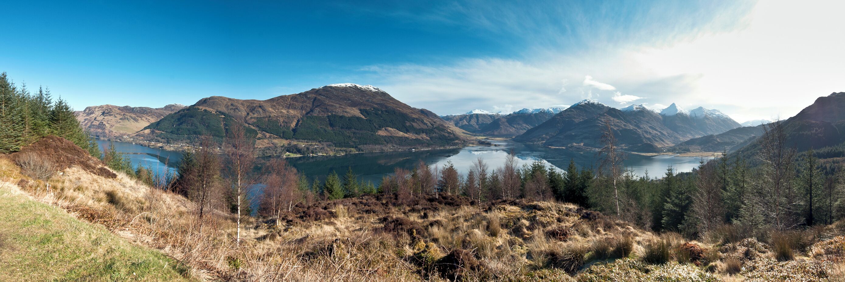 A mountainous landscape with a lake and forested areas.