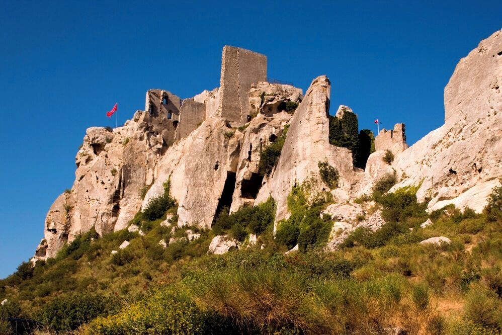 A rocky cliff with ancient ruins and a flag.