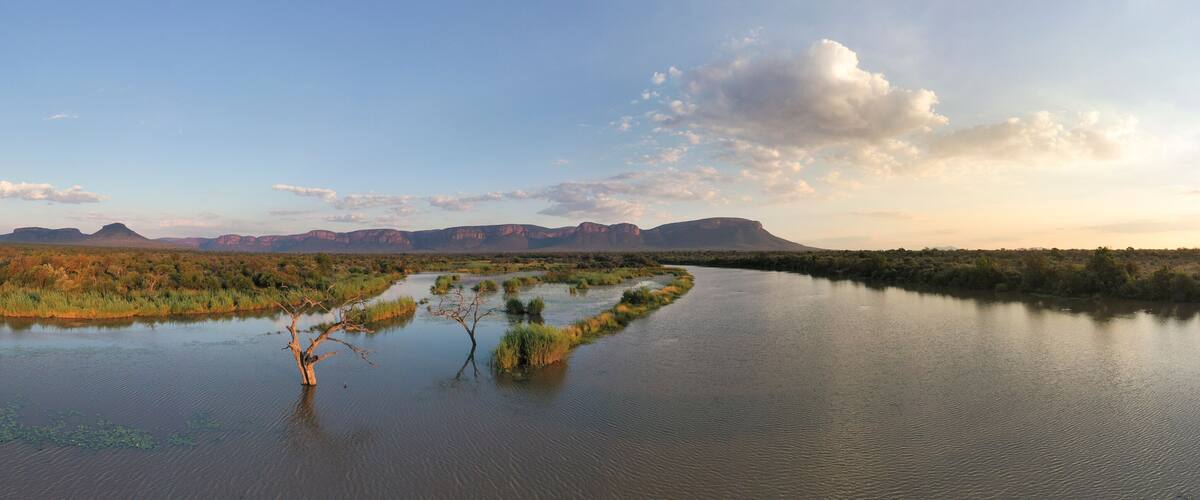 A river meandering through a landscape with sparse vegetation and distant mountains.
