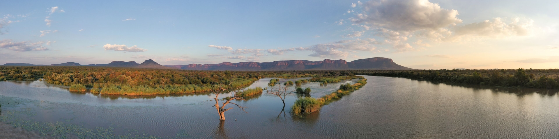 A river meandering through a landscape with sparse vegetation and distant mountains.