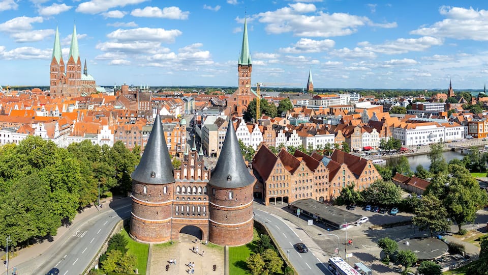 A cityscape with prominent red brick buildings, green spires, and a river.