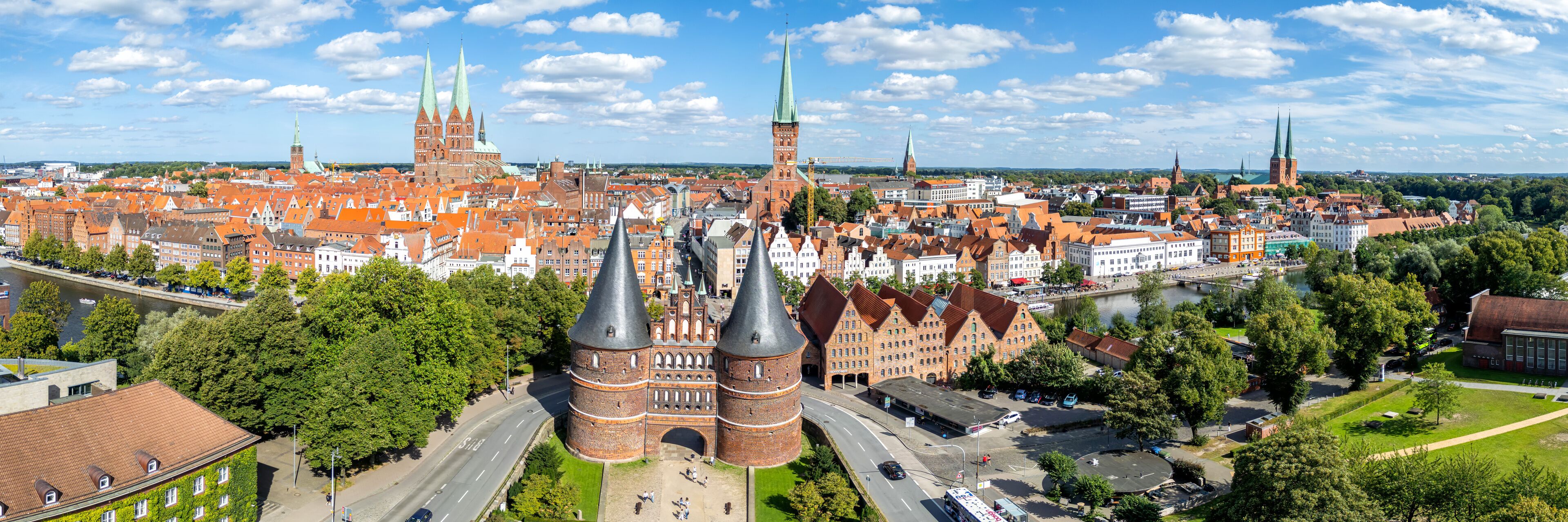 A cityscape with prominent red brick buildings, green spires, and a river.