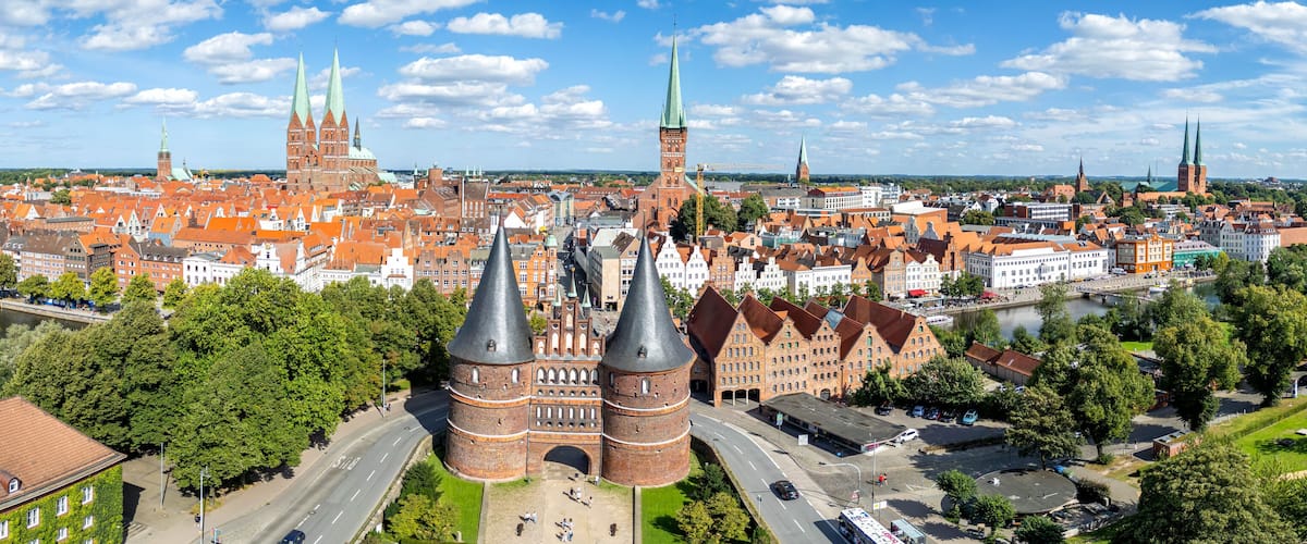 A cityscape with prominent red brick buildings, green spires, and a river.