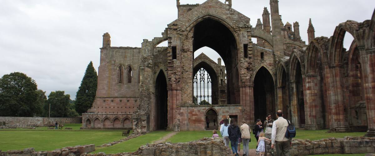 The ruins of an ancient stone building with arched doorways and a large central archway.