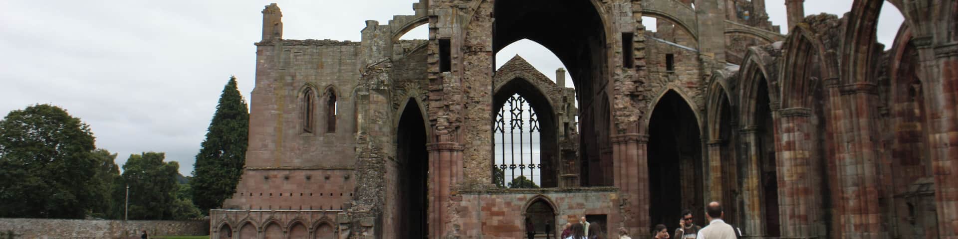 The ruins of an ancient stone building with arched doorways and a large central archway.