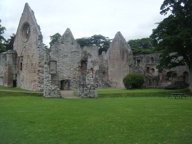 Dryburgh Abbey. Exterior view of ruins, with gatehouse over watercourse in foreground.