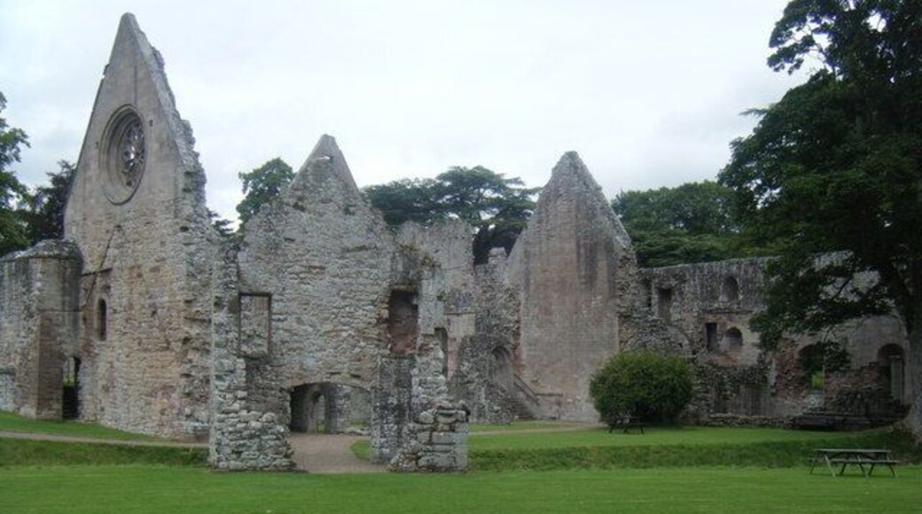 Dryburgh Abbey. Exterior view of ruins, with gatehouse over watercourse in foreground.