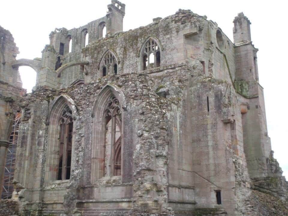 Un edificio histórico de piedra con ventanas de arco y restos de torres.