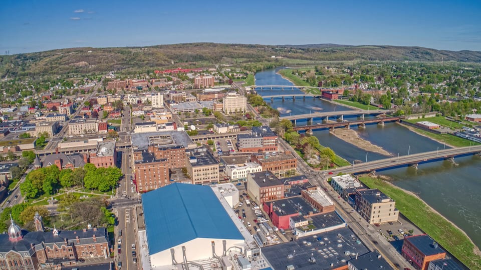 A river flowing through a city with bridges, buildings, and a hill in the background.