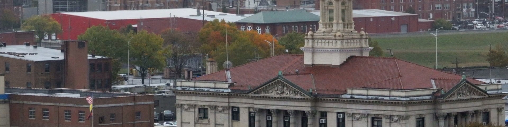 A large building with a clock tower, surrounded by other buildings and trees with autumn foliage.