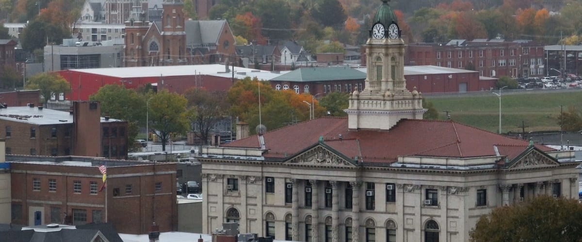 A large building with a clock tower, surrounded by other buildings and trees with autumn foliage.