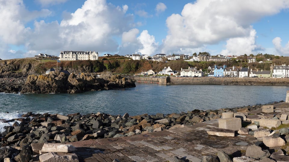 A coastal town with a lighthouse, rocky shoreline, and historic buildings.