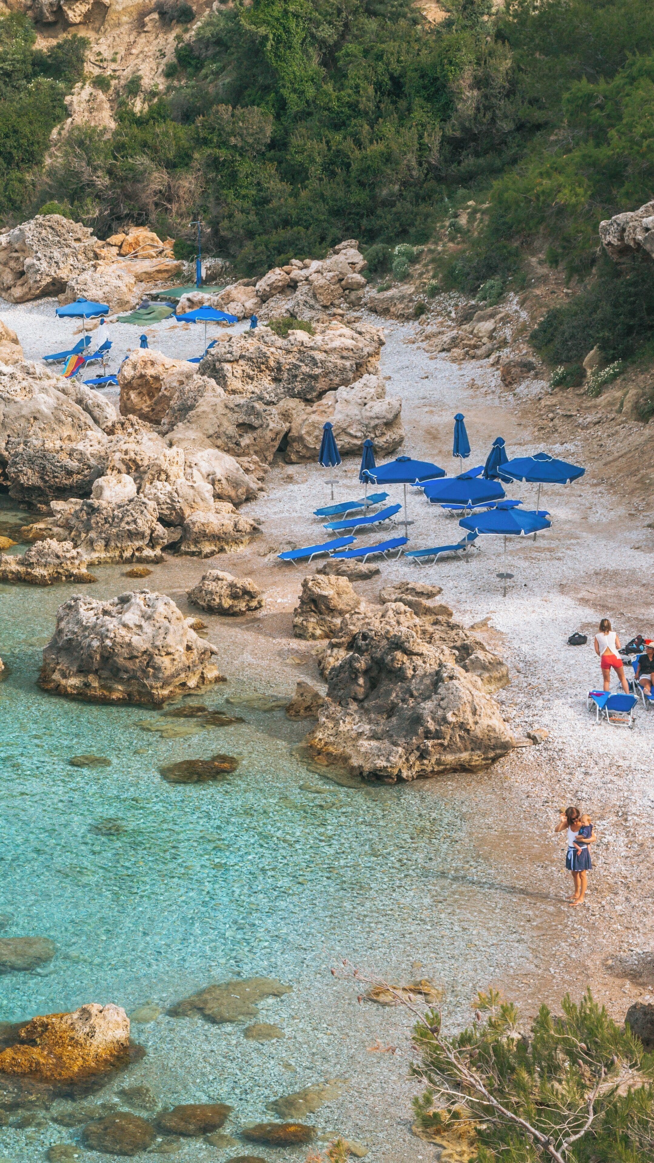 Explore the tranquil beauty of Anthony Quinn Bay in Rhodes, South Aegean, Greece with its clear waters and sun loungers by the rocky shore