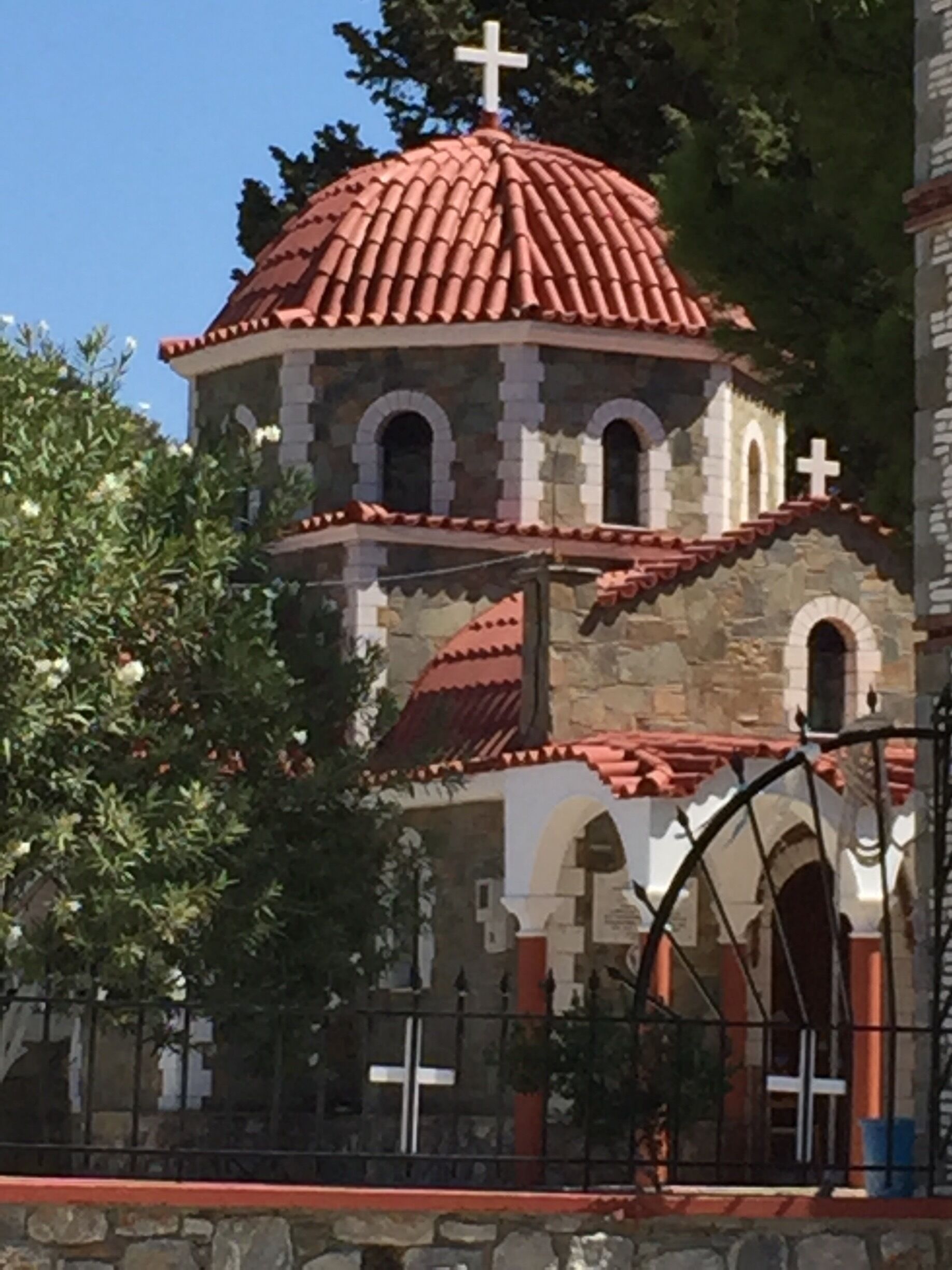 Una iglesia con cúpula de tejas rojas, paredes de piedra y ventanas en arco.