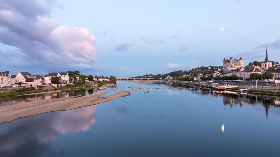 A calm river with a town on the opposite bank, featuring a prominent church and castle.