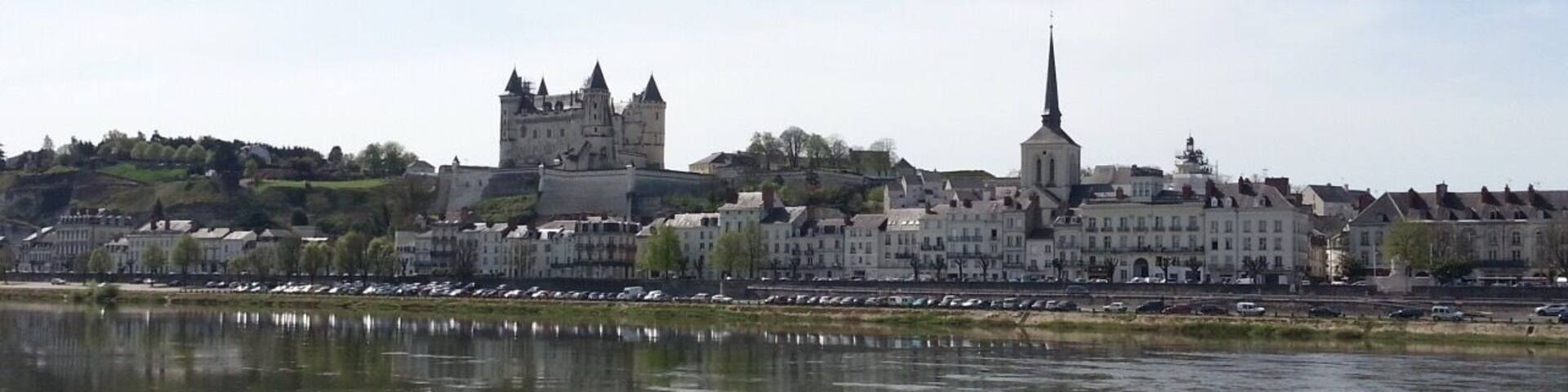 A river with a castle and a church on the opposite bank.